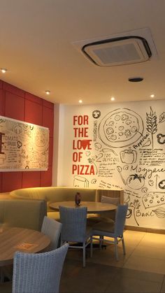 the interior of a restaurant with pizza menus on the wall and chairs around tables