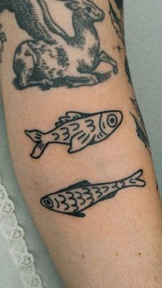 a person with tattoos on their arm and some fish in the water next to them