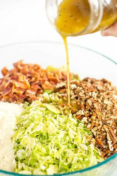 someone pouring dressing into a bowl filled with food