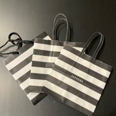 two gray and white striped shopping bags sitting on top of a black table next to each other