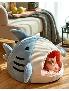 a cat in a shark shaped bed on the floor