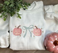 a white shirt with two pumpkins on it next to a potted plant and some other items