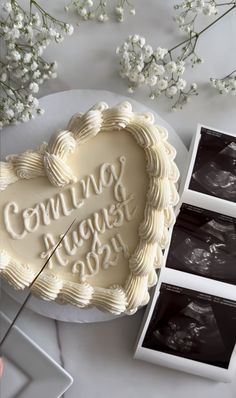 a heart shaped cake sitting on top of a table next to two boxes and flowers