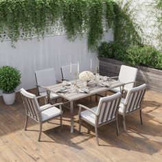 an outdoor dining table and chairs on a wooden deck next to a white planter