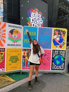 a woman standing in front of a wall with posters on it