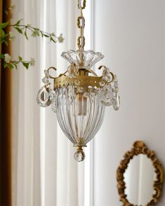 a chandelier hanging from the ceiling in front of a mirror with flowers on it