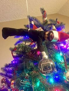 a man in a santa hat is on top of a christmas tree with his camera