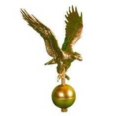 a golden eagle statue on top of a green ball with its wings spread out and taloning it's claws