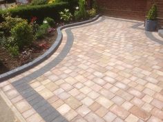 a brick driveway with landscaping around it