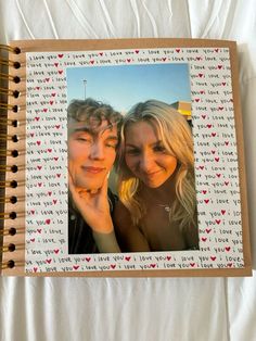 two people are posing for a photo in a wooden frame with hearts on the side