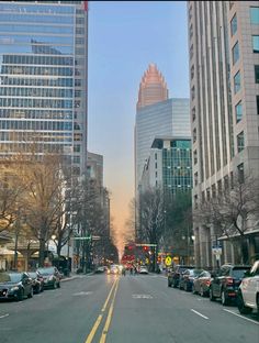 a city street with cars parked on both sides and tall buildings in the back ground