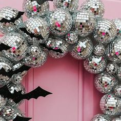 a mirror ball wreath on a pink door with a black bat hanging from the front