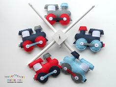 four felt toy cars are arranged in the shape of a cross on a white surface