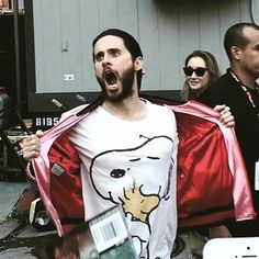 a man in a t - shirt with a cartoon character on it is holding a red cape