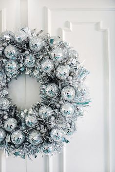 a silver christmas wreath hanging on the front door