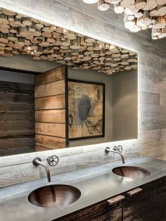 a bathroom with two sinks and wood paneling on the wall above it is an art piece