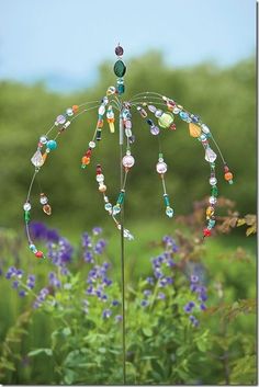 a wind chime in the middle of a field full of purple and green flowers