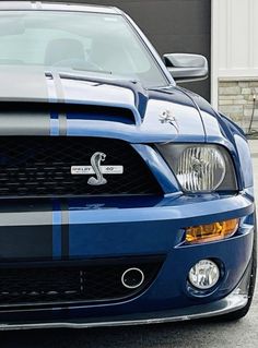 a blue mustang parked in front of a garage