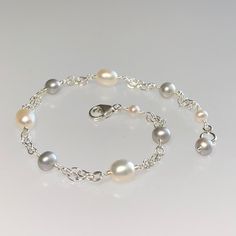 Premium-quality white and gray freshwater pearl bracelet, wire-wrapped in sterling silver This elegant and classic bracelet is designed with genuine gray and creamy-white freshwater pearls. The pearls are alternated and wire-wrapped to short segments of double strand sterling silver chain. This bracelet is completed with a sterling silver lobster claw clasp.  It is enlarged to show details.  Pearls are one of June's birthstones. Details: *  length: please choose at check-out gray semi-round f/w pearls:  3.5-4 mm  creamy white oval f/w pearls: 4x5 mm sterling silver chain and other components *  Choosing your length at checkout:  I recommend 1/2 inch larger than your actual wrist/ankle size. Bracelet/anklet is measured from end-to-end including clasp. Thanks for visiting ! Back to my shop f White Gold Pearl Bracelet, Pearl Bracelet Silver, Bridal Bracelet Pearl, Gold Pearl Bracelet, Peridot Bracelet, White Pearl Bracelet, Star Necklace Silver, June Birthstone Jewelry, August Birthstone Jewelry