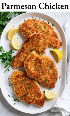 three crab cakes on a white plate with lemons and parsley next to it