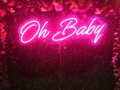 a neon sign that says oh baby on it in front of some pink and red flowers