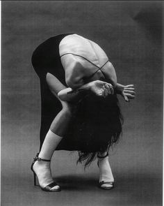 a black and white photo of a woman bending over with her legs bent in the air