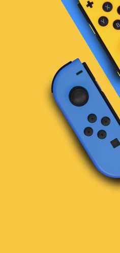 two video game controllers sitting next to each other on a yellow and blue table top