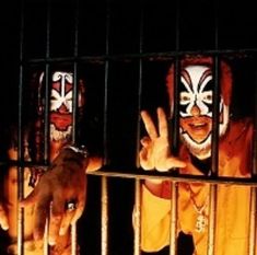 two clowns behind bars with their hands in the air and one holding his head out