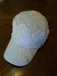 a white hat with beading on it sitting on top of a wooden table