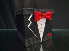 a black box with a red bow tie and diamond studs on the front is sitting on a table