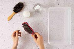 a person holding a brush next to some other items on a white table with speckles