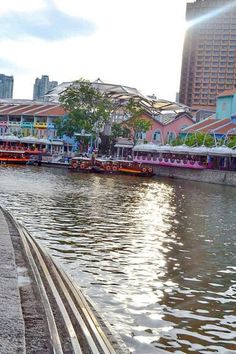 people are walking along the water in front of some buildings