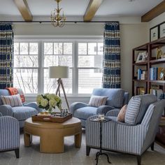 a living room filled with blue and white furniture next to a window covered in curtains