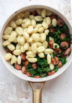 pasta and spinach are mixed together in a skillet on the stove top, ready to be cooked