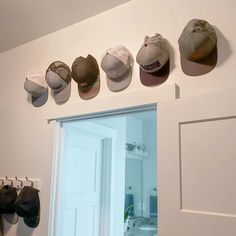 there are many hats hanging on the wall above the door and in front of the mirror