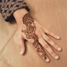 a woman's hand with a henna tattoo on her left arm and wrist