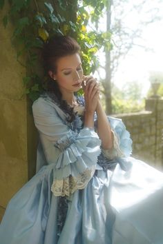 Immerse yourself in the splendor of a bygone era with our Sky Blue Rococo Ball Gown, an exquisite creation crafted for those who covet timeless elegance. This dress is a harmonious blend of the lavishness of the Rococo period and the grandeur of Baroque fashion, designed to enrobe you in a spectacle of courtly allure.The soft sky blue satin fabric drapes gracefully, cascading in sumptuous folds that reflect the light with every movement, embodying the opulent lifestyle of Marie Antoinette hersel Blue Rococo Style Costume Dress, Blue Rococo Costume Dress, Blue Baroque Vintage Dress, Blue Vintage Baroque Dress, Vintage Blue Baroque Dress, Blue Baroque Wedding Dress, Blue Baroque Dress With Historical Design, Elegant Baroque Dress With Fitted Bodice, Elegant Dresses With Fitted Bodice In Baroque Style