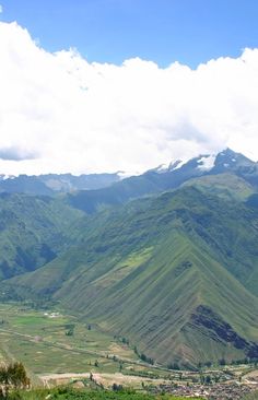 the mountains are covered in green grass and clouds