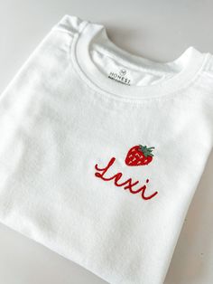 So adorable! Each name will be stitched below an embroidered strawberry. These are embroidered on Honest organic cotton tees or organic cotton bodysuits.  If you are wanting a different design, more wording, or a different clothing style, please send me a message so we can discuss the details. Organic White Crew Neck Tops, White T-shirt With Letter Embroidery As Gift, Gift Red Embroidered Top, Red Embroidered Tops Gift, Red Embroidered Tops As Gift, Red Embroidered Top For Gift, Cute White T-shirt With Machine Embroidery, White T-shirt With Machine Embroidery As Gift, White T-shirt With Letter Embroidery For Gift