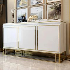 a white and gold sideboard with pictures on the wall