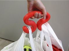 a person is holding two bags with red handles and one has a green ball in it