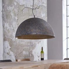 a wooden table with a bottle of wine on it and a light fixture hanging from the ceiling