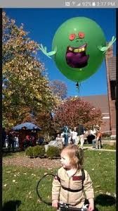 a young child sitting on the ground in front of a green balloon with an angry face