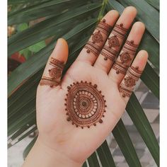 a woman's hand with henna tattoos on it and palm leaves in the background