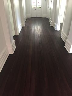 an empty hallway with wood floors and white trim on the walls is seen in this image