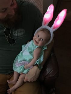 a man holding a baby wearing bunny ears