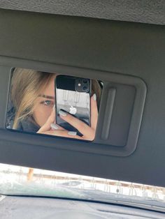 a woman taking a selfie in the back seat of a car with her cell phone