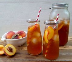 two mason jars filled with liquid and peaches next to a bowl of sliced peaches