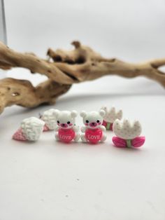 four little white teddy bears sitting next to each other in front of a tree branch