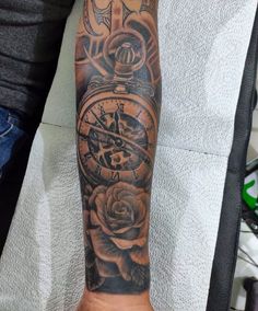 a man's arm with a clock and roses tattoo on the forearm, in black and grey